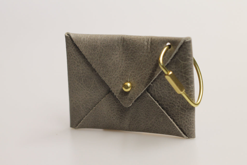 Gray envelope-shaped pouch with a gold clasp on a light gray background